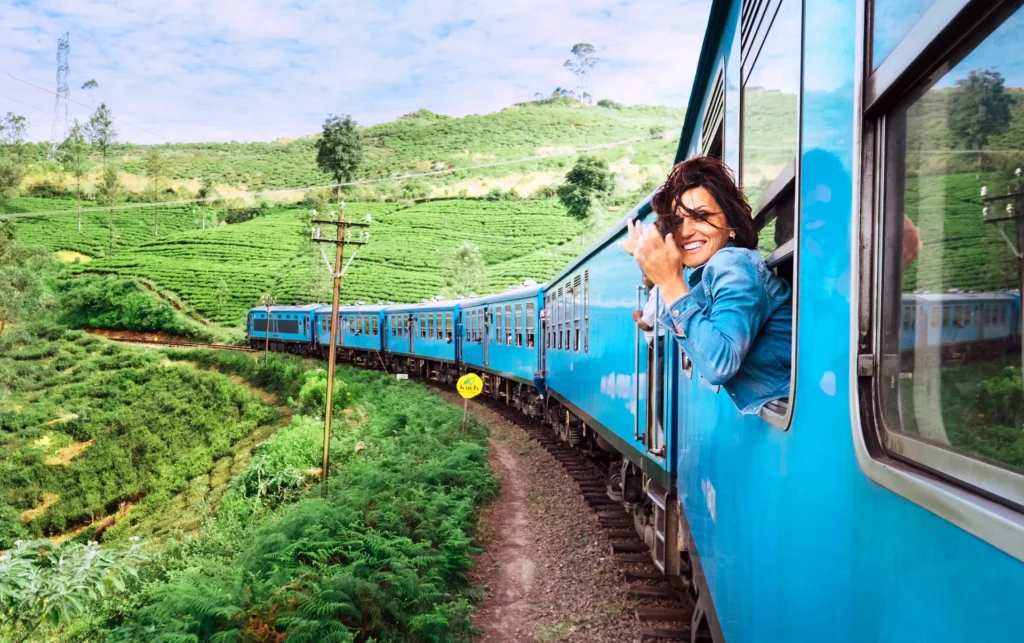 A blue train traverses surrounded by lush Sri Lankan mountains.